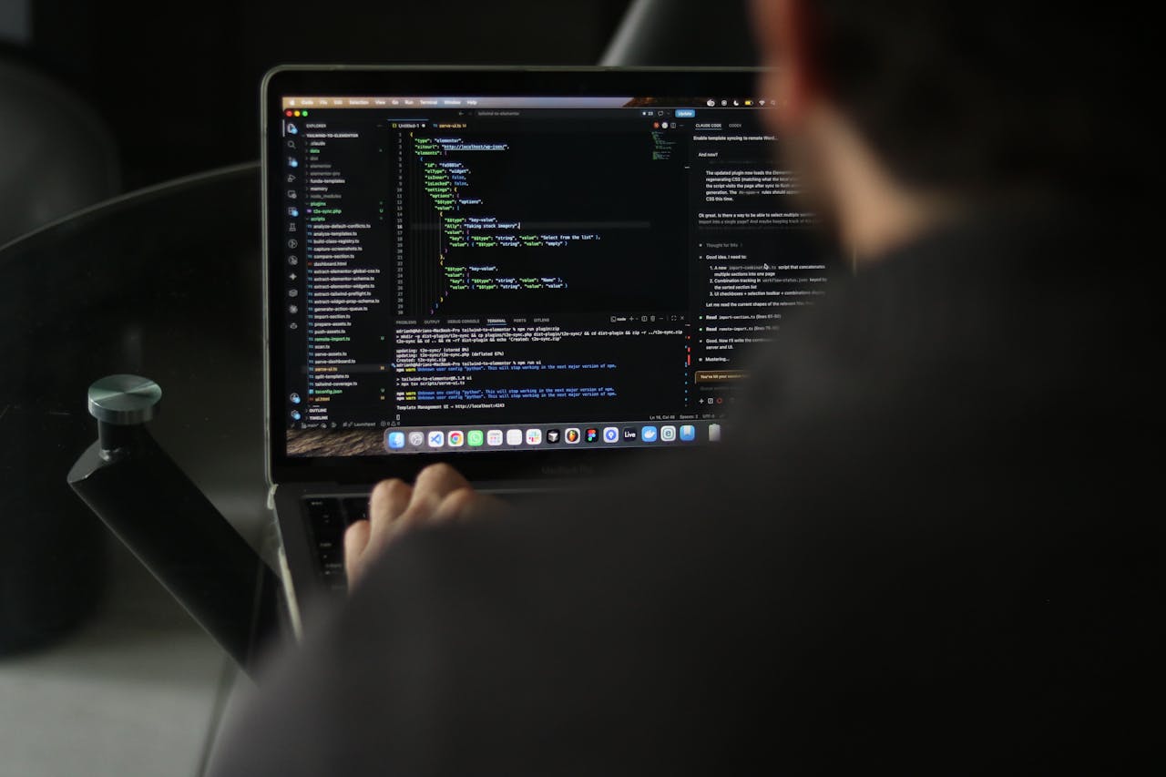 A focused developer writing code on a laptop in an indoor workspace.